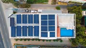 An aerial view of a building with multiple solar panels and a swimming pool.