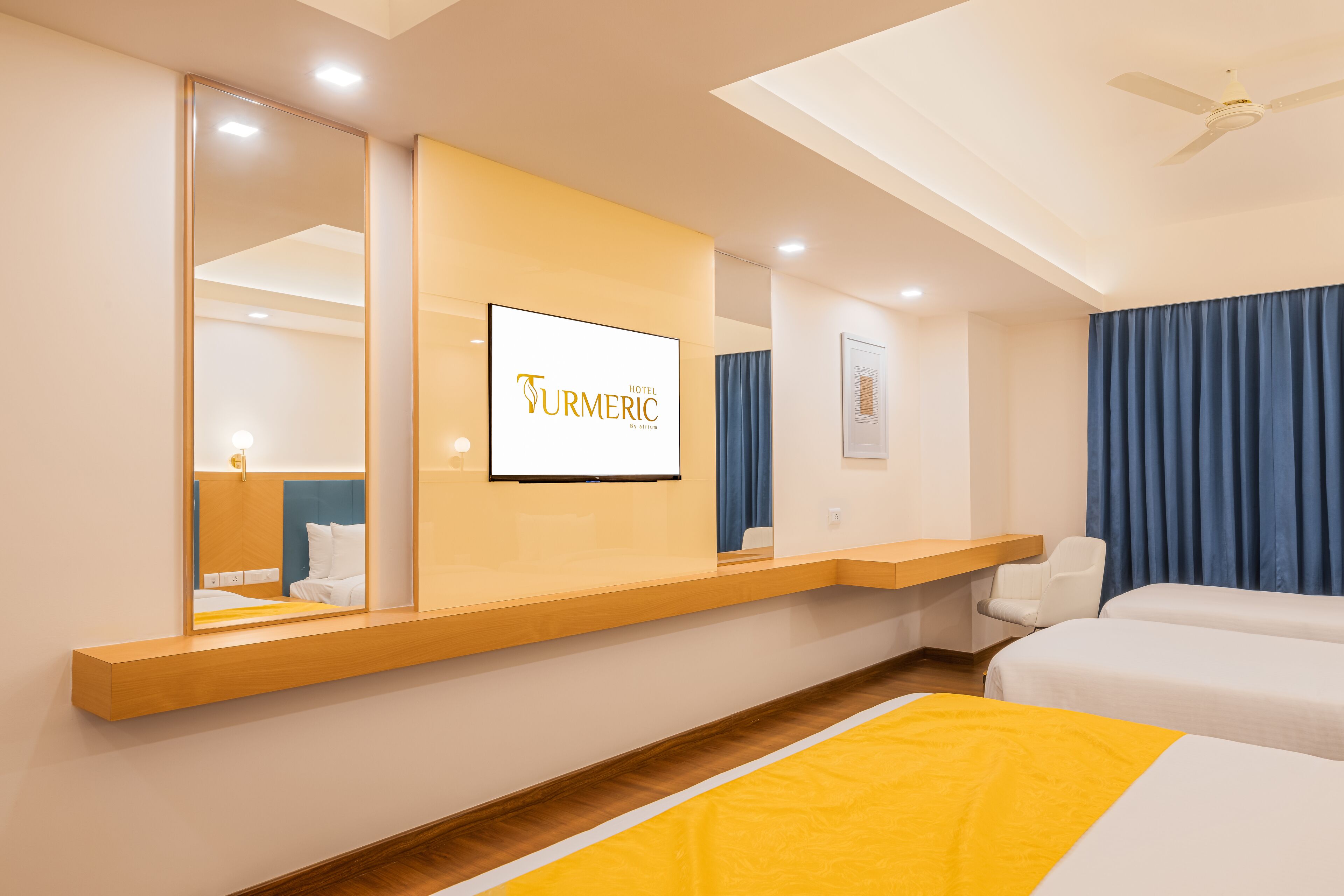 A hotel room with a bed, a desk, a chair, a TV, and a ceiling fan.