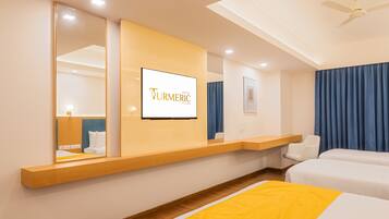 A hotel room with a bed, a desk, a chair, a TV, and a ceiling fan.