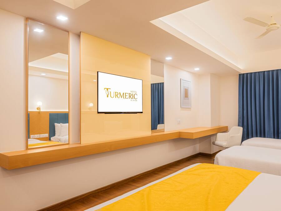 A hotel room with a bed, a desk, a chair, a TV, and a ceiling fan.