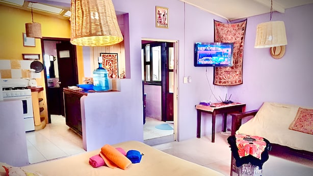 A room with a bed, a television, a kitchen area, and a dining table. - Cozy Vacation Rental in San Cristóbal de las Casas (San Cristóbal de las Casas)