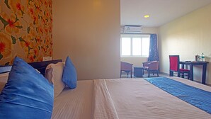 A hotel room with a bed, a desk, a chair, and a window. - Hotel NS Royal Emirates (Hyderabad)