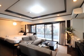 Een hotelkamer met een bed, een bank, een salontafel, een televisie en een groot raam.
