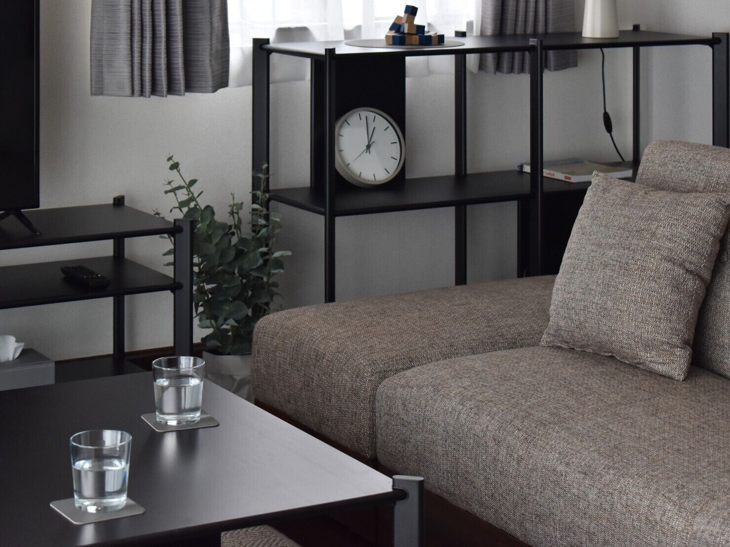 A modern living room with a sofa, a coffee table, a bookshelf, and a clock.