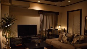 A modern living room with a flat-screen TV, a sofa, a coffee table, and a lamp. - Sunmall Crest607 (Tokyo)