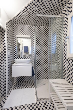 Features a bold black and white checkered tile pattern, a large mirror, and a sleek glass-enclosed shower area.