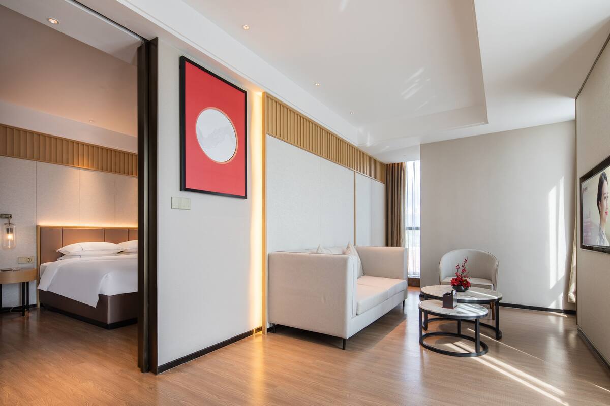 A modern hotel room with a bed, a sofa, a small table, and a chair.