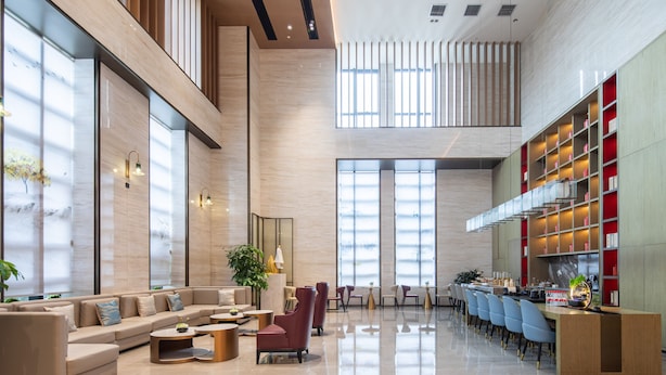 Eine geräumige Lobby mit modernem Design, ausgestattet mit einer großen Sitzecke, einem Empfangstresen und einer gut beleuchteten Umgebung mit Tageslicht.