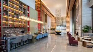 Eine moderne Hotelhalle mit Barbereich, Sitzgelegenheiten und einer großen Pflanze.