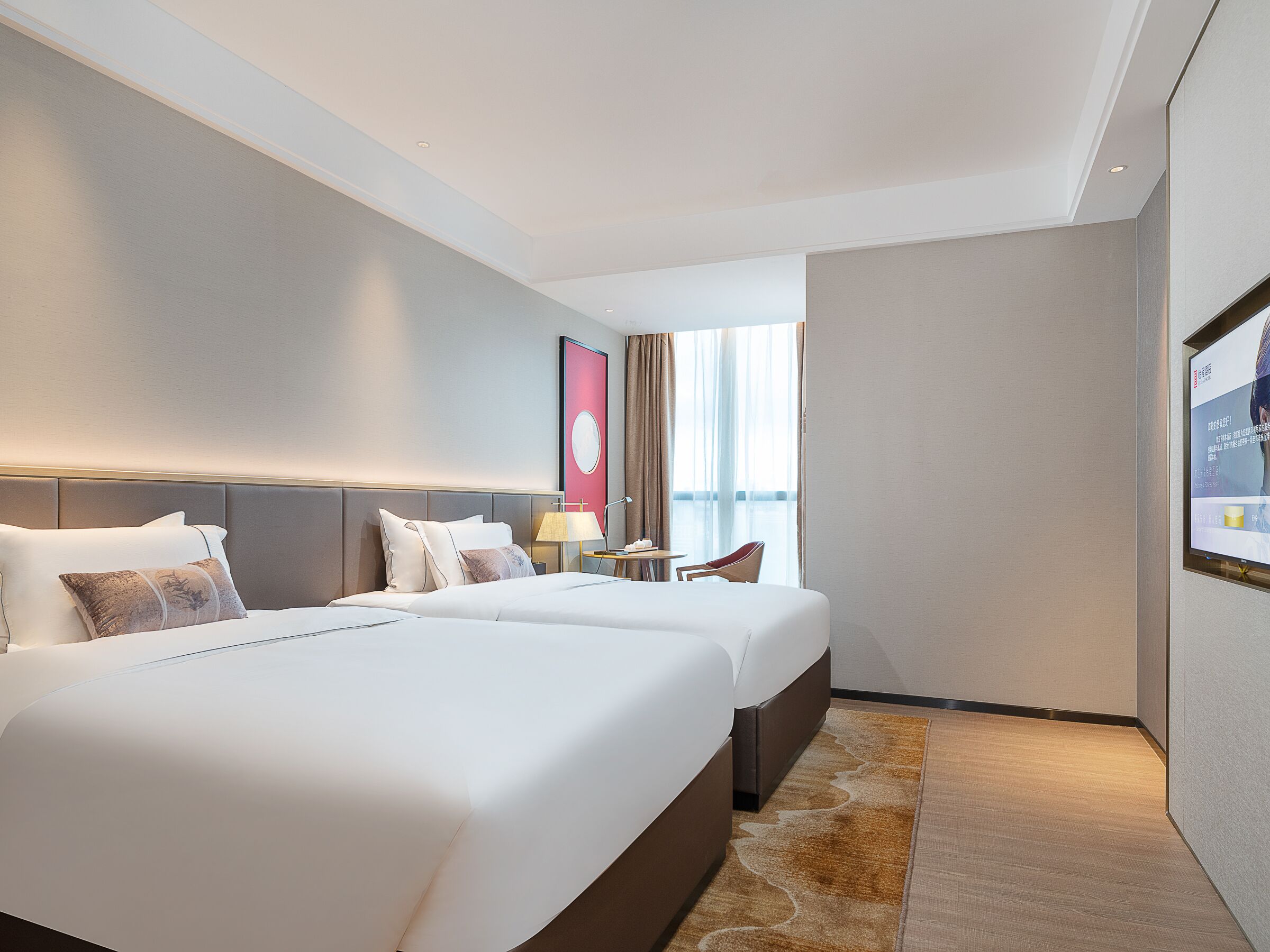 A hotel room with two beds, a nightstand, a lamp, a chair, and a large window with curtains.