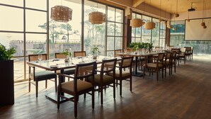 Un amplio comedor con ventanas grandes, mesas y sillas de madera.