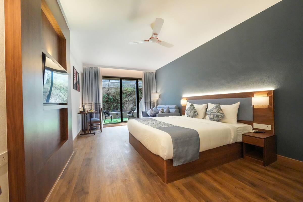 A modern bedroom with a large bed, a ceiling fan, and a view of the outdoors.