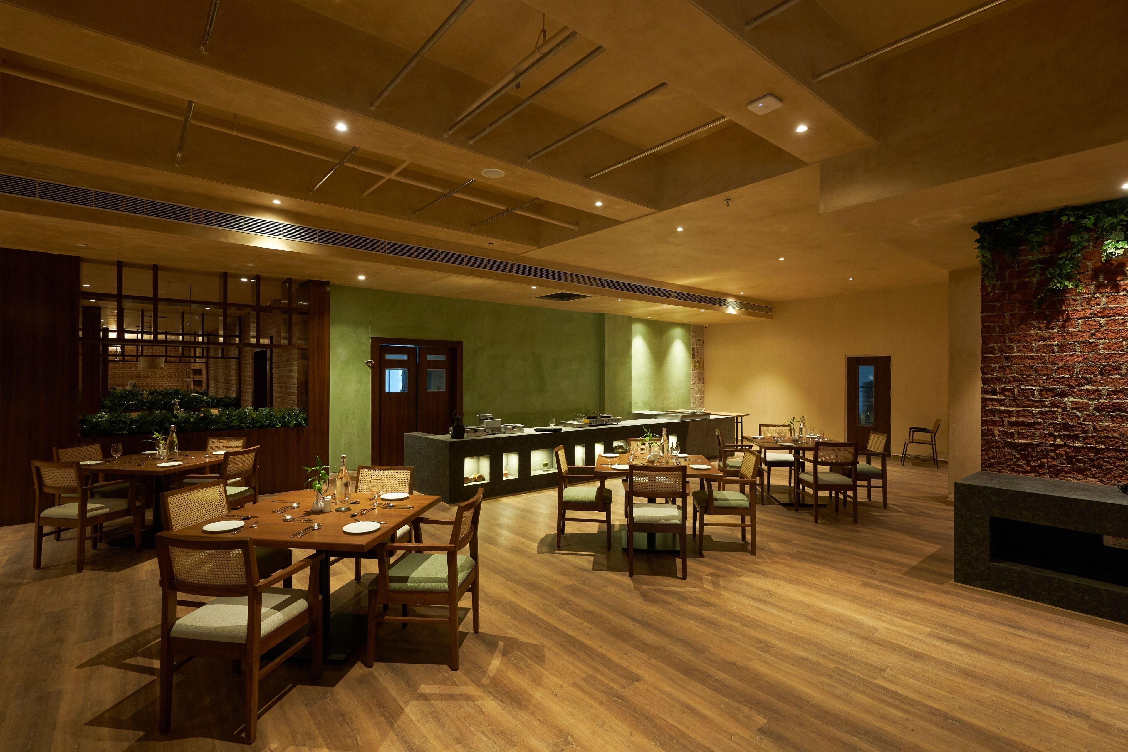 A spacious dining area with wooden tables and chairs, a bar counter, and a brick wall accent.