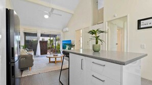 Une cuisine moderne dotée d’un grand îlot central, de meubles blancs et d’un ventilateur de plafond.