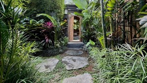 Un sendero en un jardín que lleva a una estructura de madera con techo de tejas.