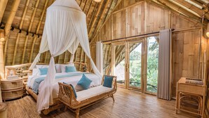 Una habitación con cama, muebles de mimbre y amplias ventanas.