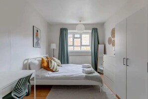 A modern bedroom with a bed, a desk, and a wardrobe.