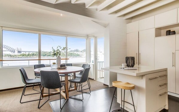 Una cocina moderna con comedor, ventanas amplias y vistas a un puente.
