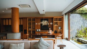 A modern interior with a wooden dining area, a large column, and a view of a water feature outside. - Kolila Villa Seminyak by Ini Vie Hospitality (Kerobokan)