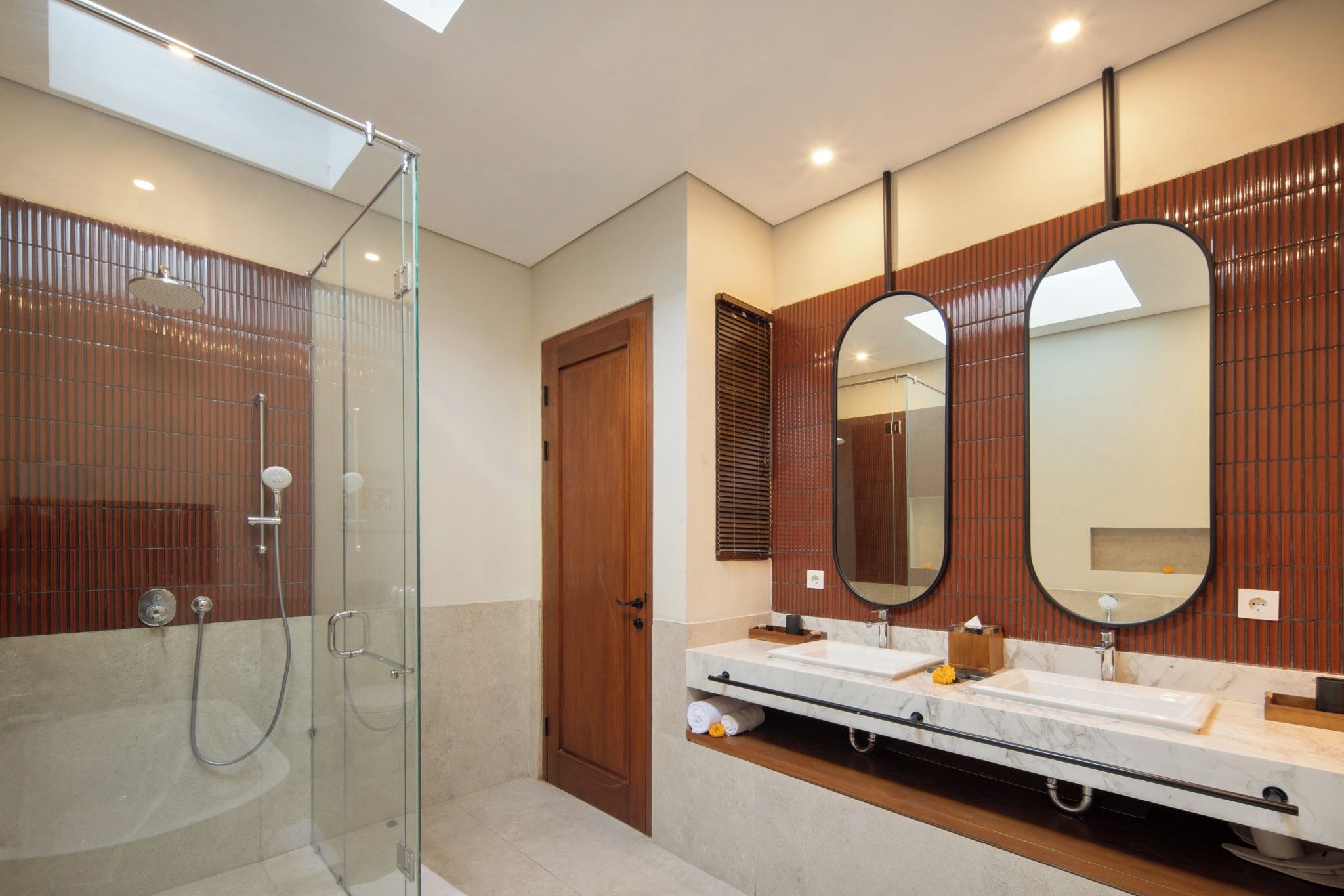 A modern bathroom with a glass-enclosed shower, two sinks, and large mirrors.