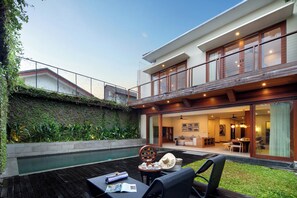 A modern house with a pool, outdoor seating, and a dining area.