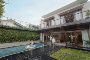 A modern house with a swimming pool, a covered outdoor area, and a well-maintained garden.