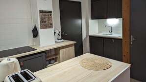 A compact kitchen with a wooden countertop, a coffee machine, a toaster, and dark cabinets. - Gîte La P'tite Lulu à St Pierre D'entremont, à Côté Cirque de St Même (Saint-Pierre-d'Entremont)