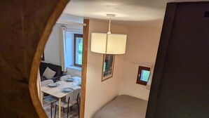 A compact bedroom with a bed, a small window, and a dining area with a table and chairs. - Gîte La P'tite Lulu à St Pierre D'entremont, à Côté Cirque de St Même (Saint-Pierre-d'Entremont)