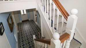 Una escalera con balaustres blancos y barandilla de madera, que sube a un nivel superior.