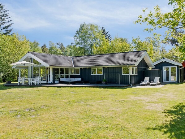 A two-story house with a covered patio, a fenced yard, and a small shed.