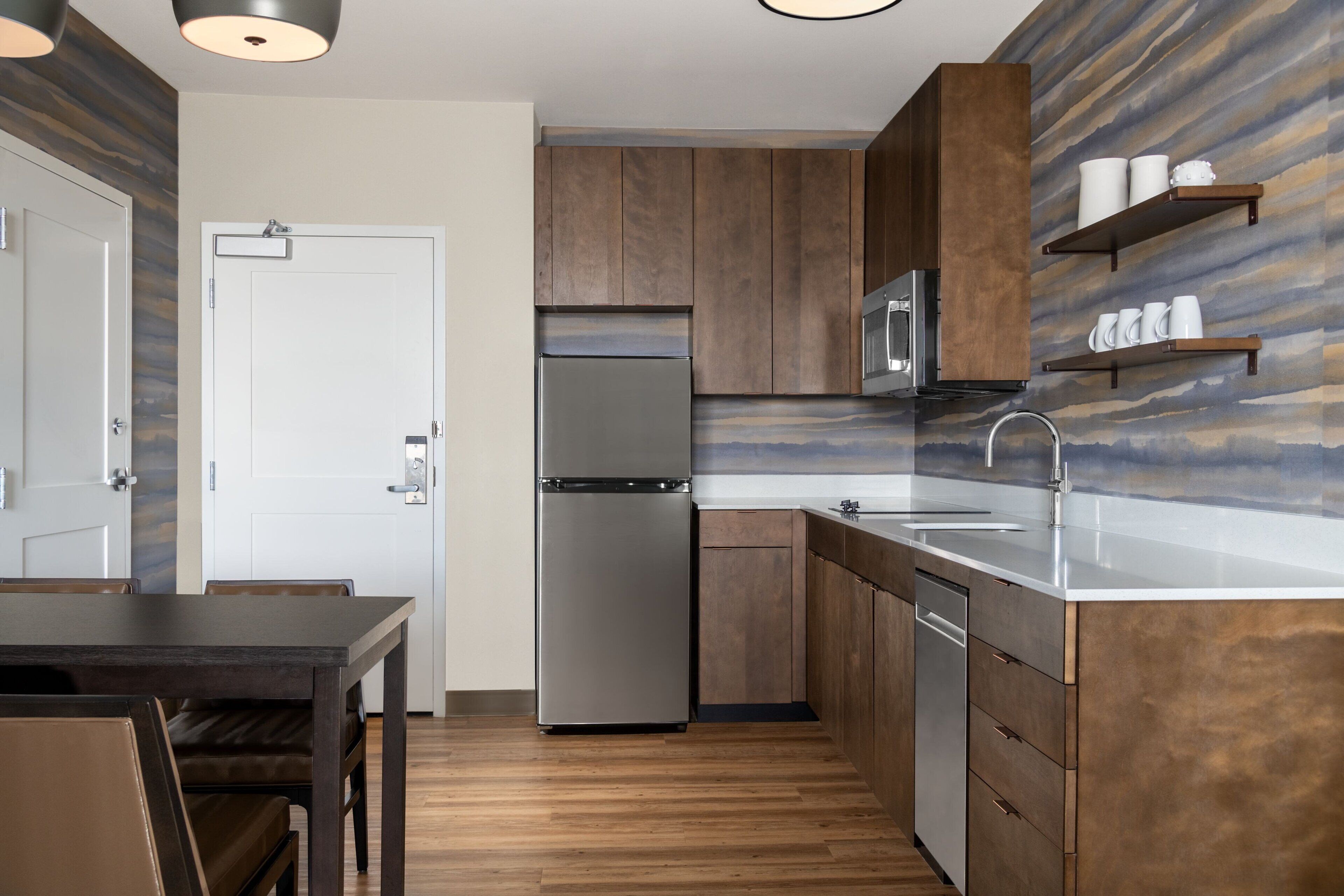 Una cocina moderna con armarios de madera, electrodomésticos de acero inoxidable y una mesa de comedor de madera.