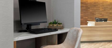 Ein moderner Arbeitsplatz mit Schreibtisch, Computer, Tastatur und einem gepolsterten Stuhl.