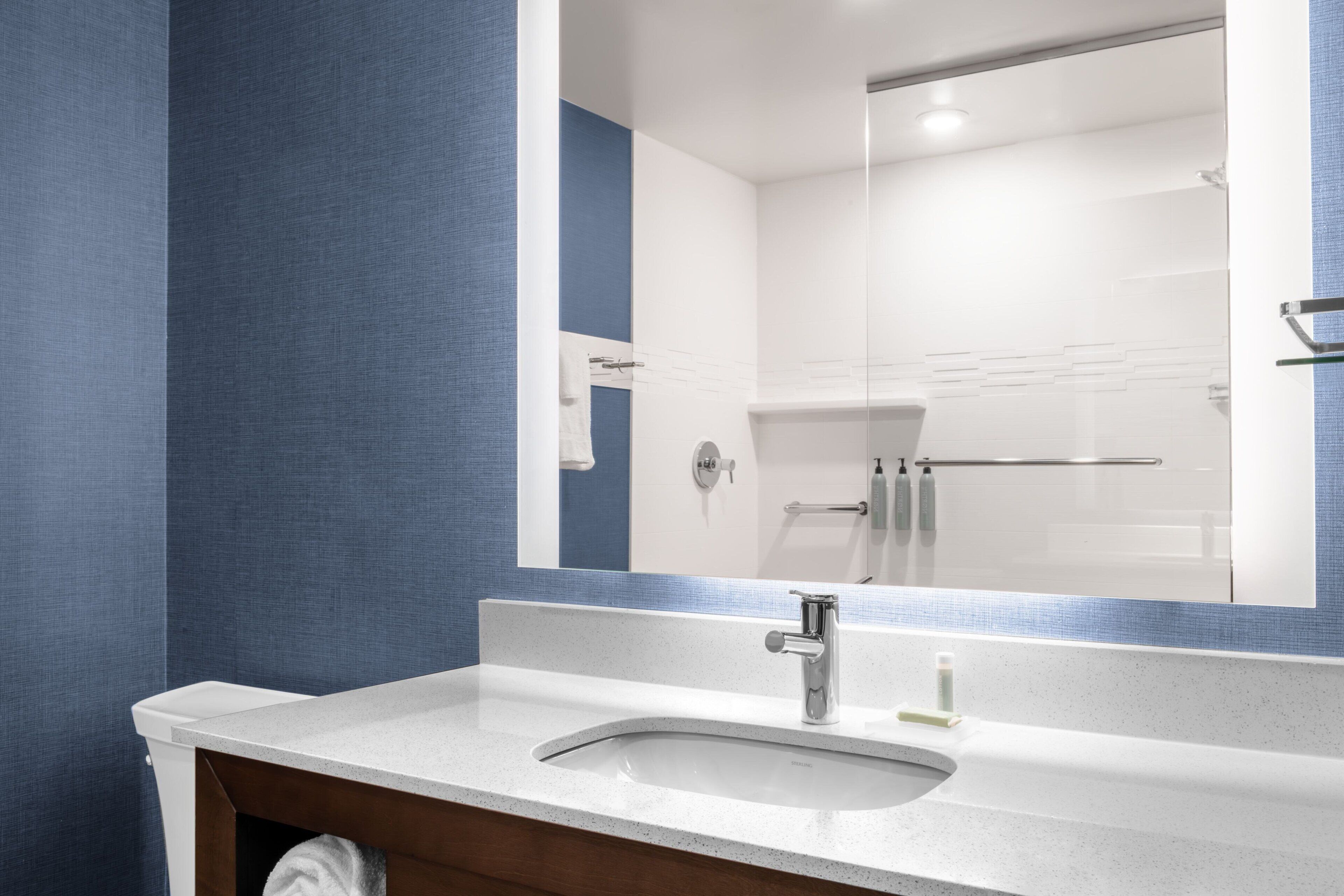 Une salle de bain avec un lavabo blanc, un miroir et un porte-serviettes.