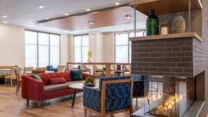 A modern lounge area with a fireplace, comfortable seating, and large windows. - Residence Inn by Marriott Arvada Denver West (Arvada)