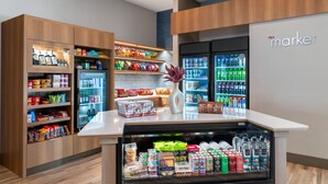 A grocery store interior with refrigerated sections, shelves stocked with snacks, and a 'market' sign on the wall. - Residence Inn by Marriott Arvada Denver West (Arvada)