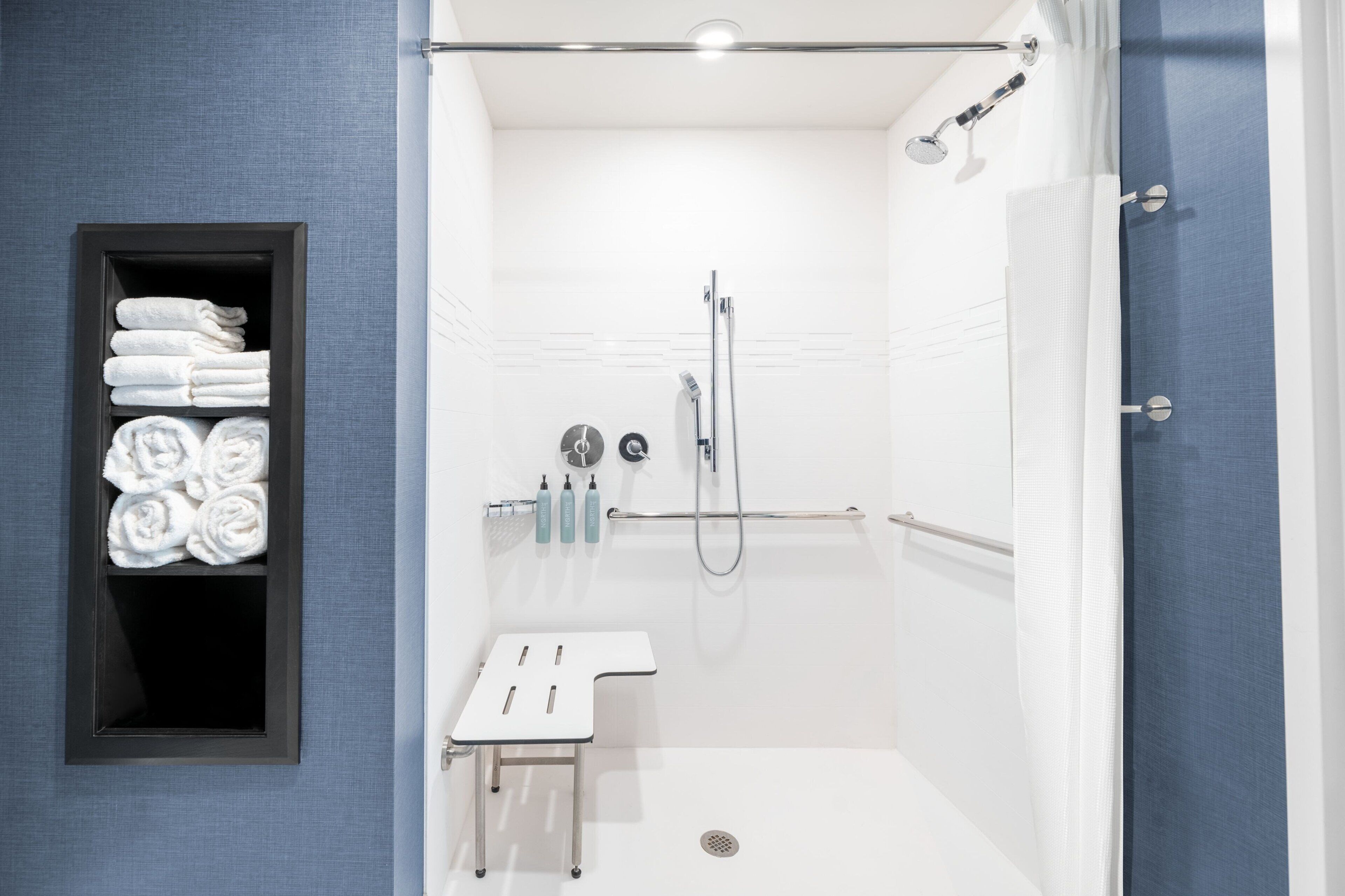 A modern bathroom with a shower, a towel rack, and a small table.
