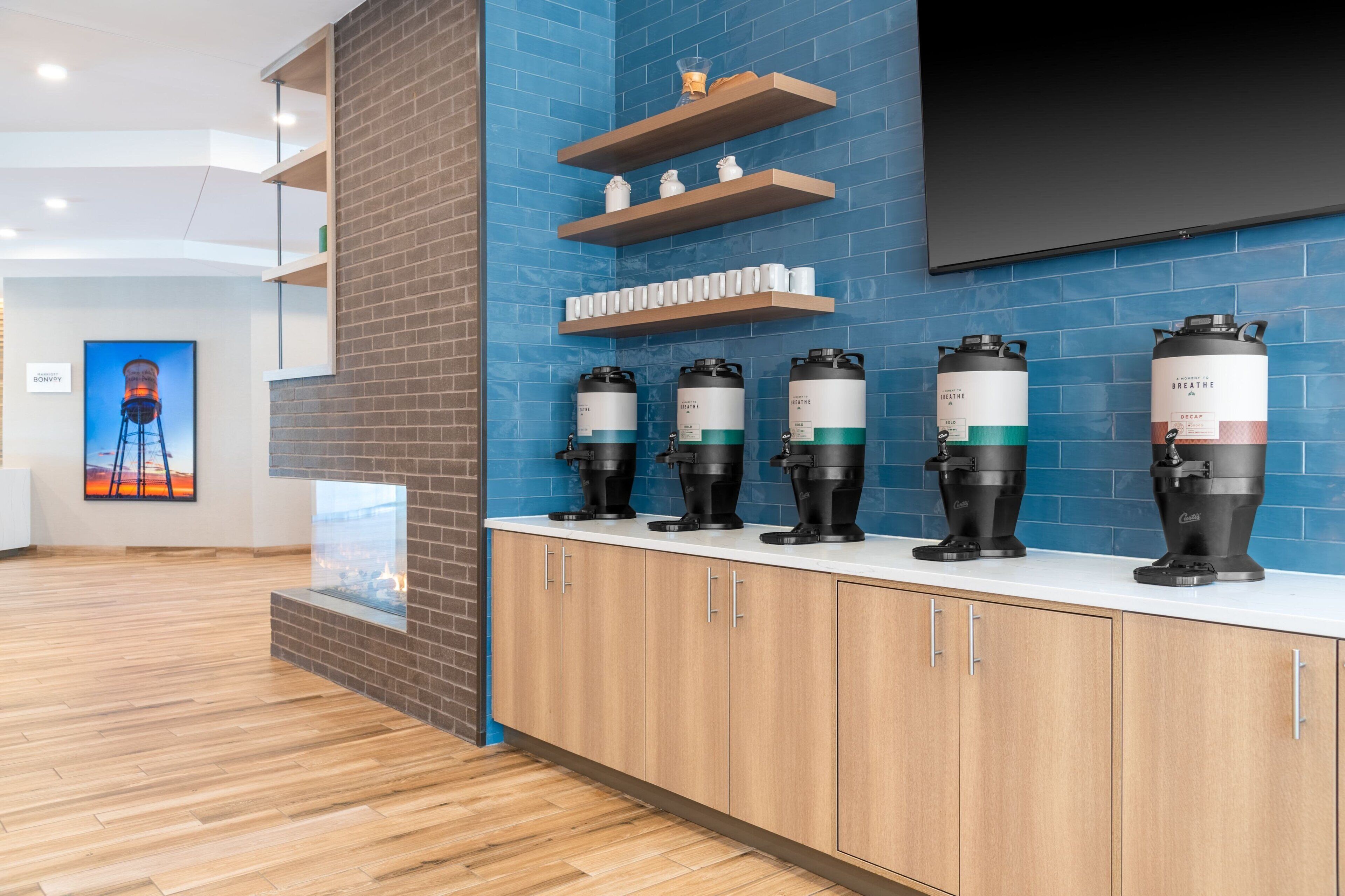 A modern kitchen with a brick accent wall, wooden cabinets, and a built-in coffee station with four coffee makers.