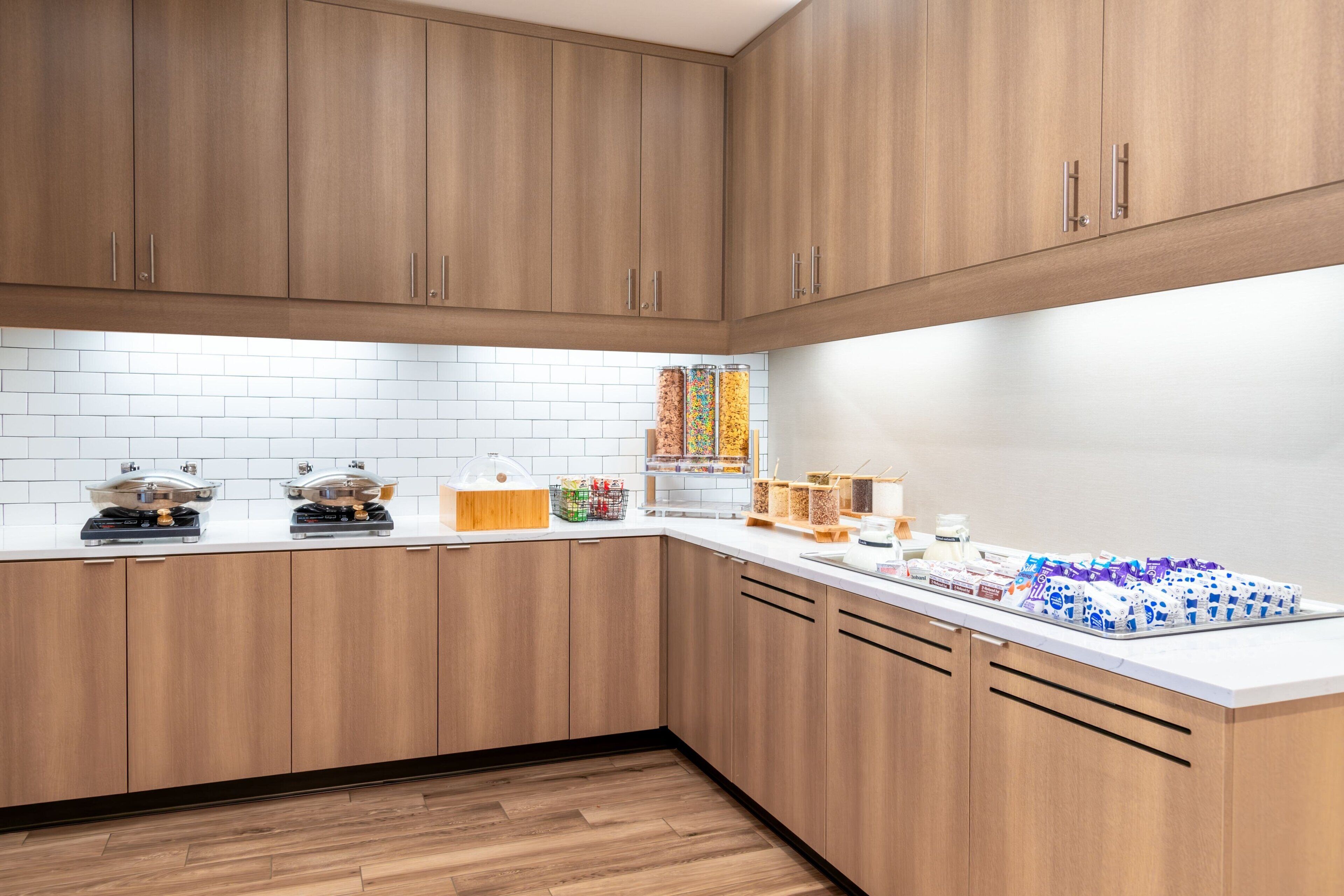 Une cuisine moderne avec des meubles en bois, des plans de travail blancs et divers appareils de cuisine.