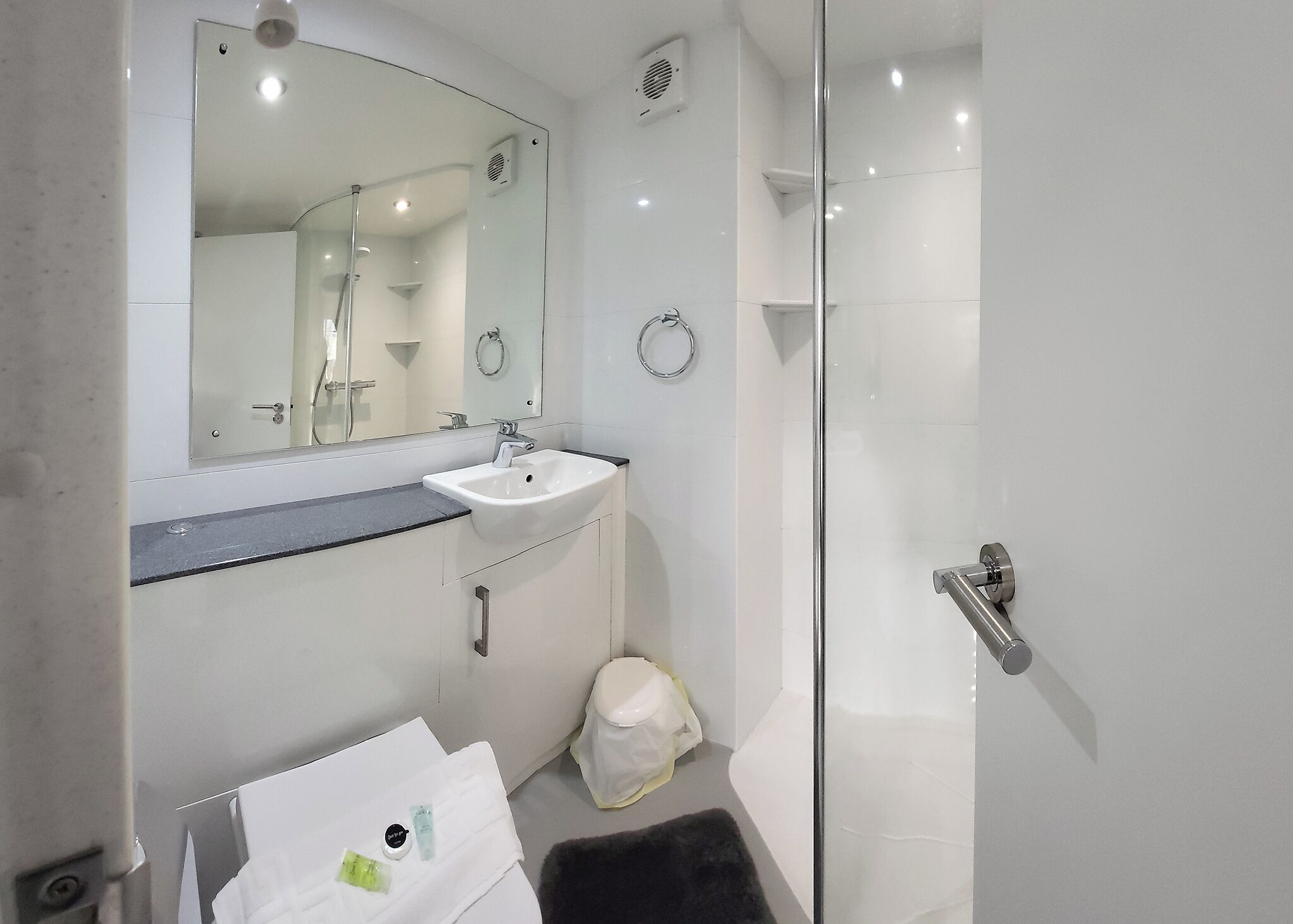 Une salle de bain moderne avec une douche à parois de verre, un lavabo blanc et un miroir au-dessus.