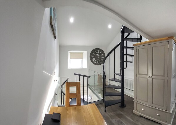 A staircase with a wooden handrail, a black clock, and a cabinet.