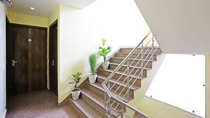 A staircase with metal railings, potted plants, and a door with a number sign. - Hotel Broadway (New Delhi)