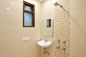 A bathroom with a sink, mirror, shower, and a window. - Hotel Broadway at Airport (New Delhi)