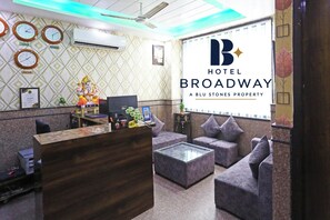 A hotel reception area with a reception desk, seating, clocks, and a large sign for Hotel Broadway. - Hotel Broadway at Airport (New Delhi)