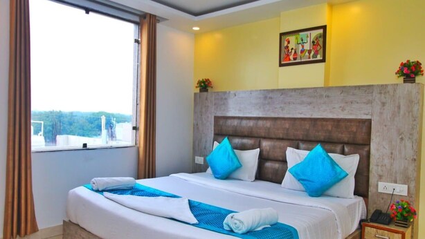 A hotel room with a large bed, a wooden headboard, and a window with curtains. - Hotel Broadway (New Delhi)