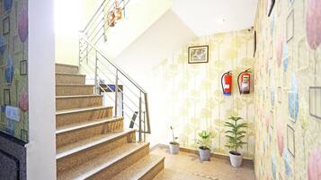 A staircase with metal railings leading to a landing. There are three potted plants on the landing.