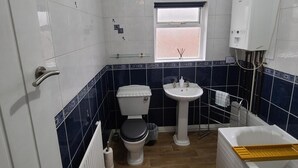 Een kleine badkamer met toilet, wastafel en bad.