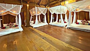 A room with four beds, each with a canopy, in a rustic wooden room with a high ceiling and exposed beams. - Pu Luong May Home & Cafe  (Pu Luong)