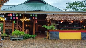 A restaurant with a thatched roof, wooden deck, and neon signs. - Pu Luong May Home & Cafe  (Pu Luong)