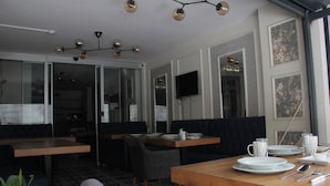 A dining area with a wooden table set for two, a television mounted on the wall, and a patterned floor. - Solo Suites Hotel (Istanbul)
