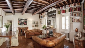 Una sala de estar acogedora con chimenea, sofás de cuero, una mesa de comedor y una estantería llena de libros.